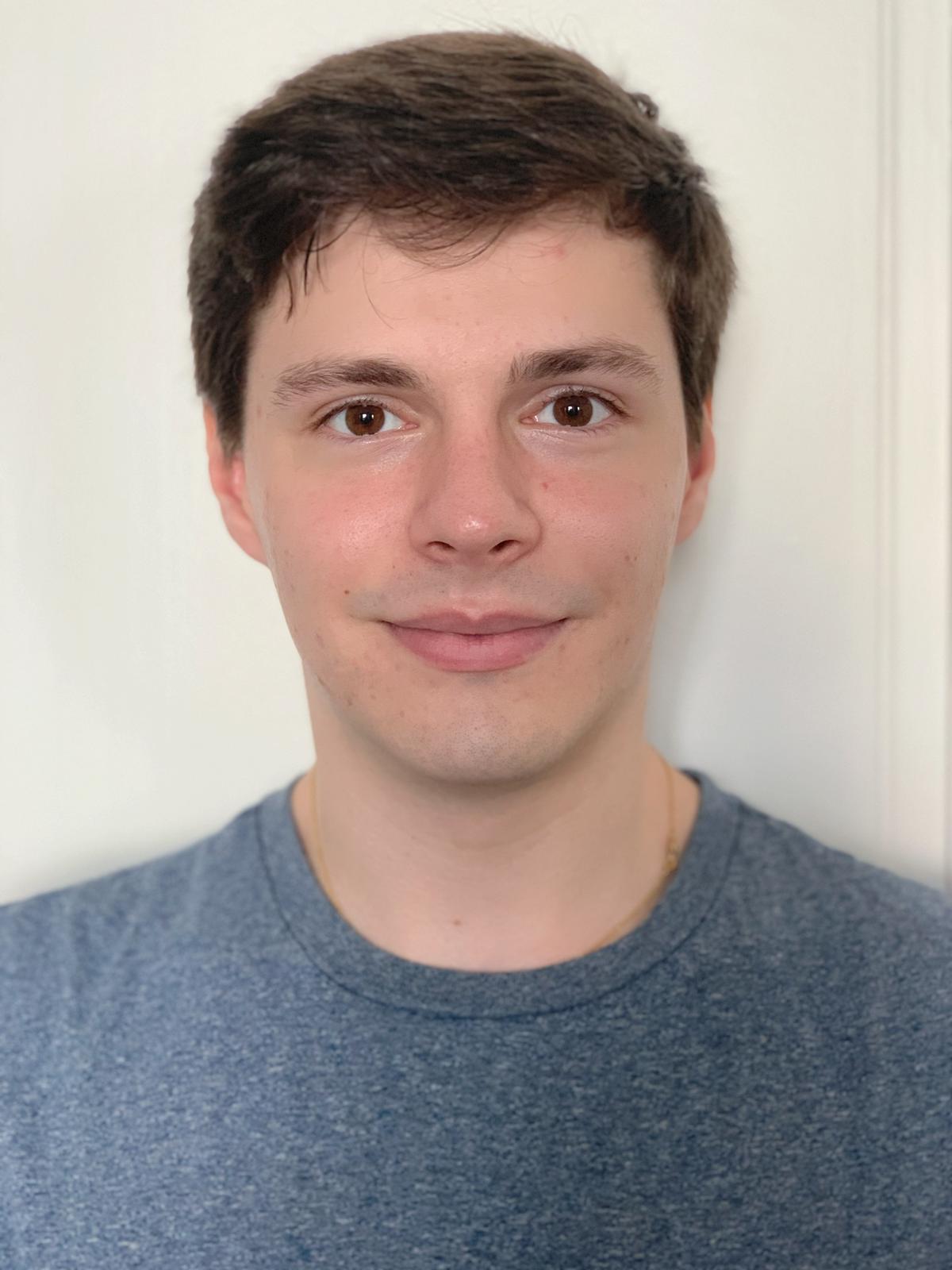 A picture of Alexandre, a white man with brown hair, wearing a blue t-shirt with a white background.