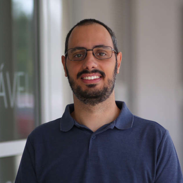 A portrait of Daniel Mendes, who has a beard and is wearing glasses and a blue polo shirt.